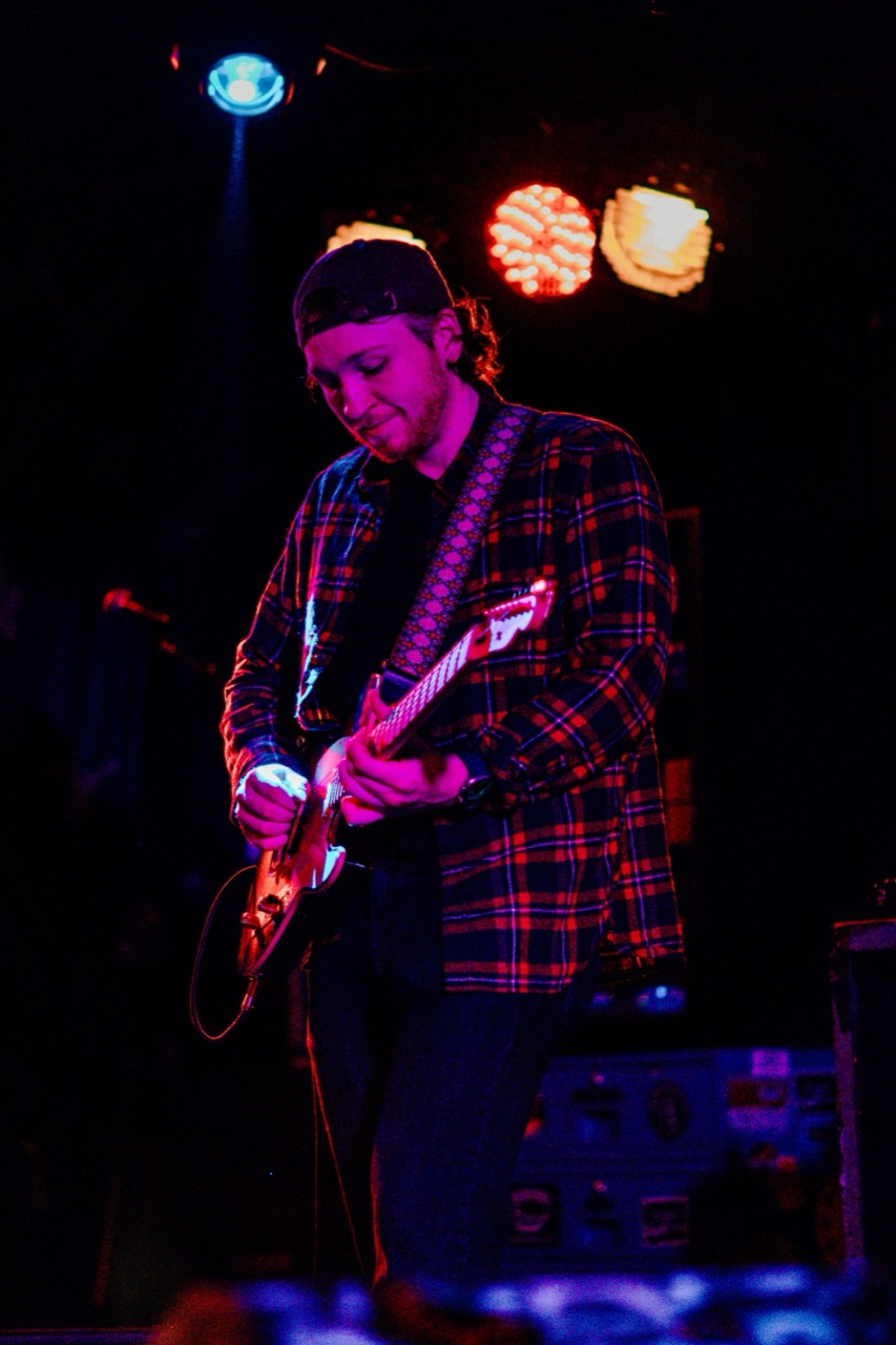 Something Like Mercury guitarist performing under colorful stage lights
